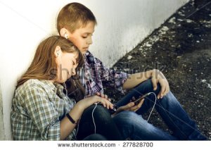 stock-photo-teens-boy-and-girl-sitting-next-to-a-white-wall-they-listen-to-music-from-the-phone-enjoy-the-277828700